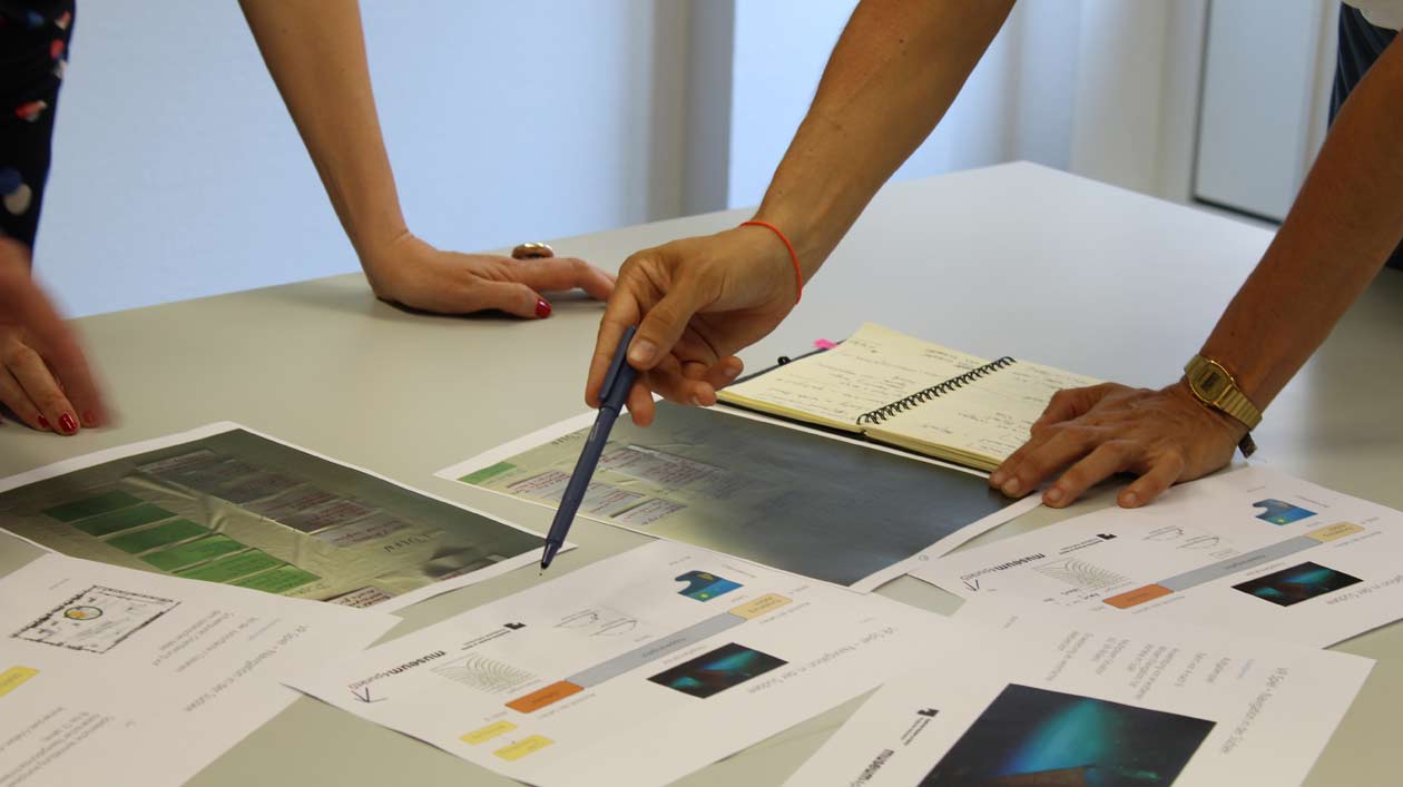 Hands point at different papers on a table