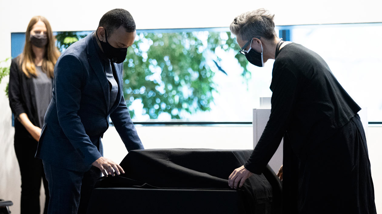 Two people cover two boxes on a small table with a black cloth