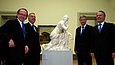 Vier Männer stehen um eine Skulptur in einem Ausstellungsraum