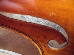 Detailaufnahme eines Geigenzettels mit dem Namen Antonio Stradivari im Inneren eines Streichinstruments.