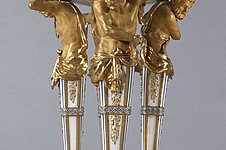 Four partially gilded figures standing on a base support a decorated basket
