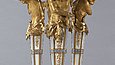 Four partially gilded figures standing on a base support a decorated basket