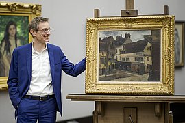 Museumsleiter Ralph Gleis steht lächelnd neben der Staffelei mit dem Pissarro-Gemälde