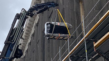Kran hebt schweren Gegenstand aus Fenster