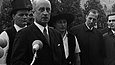 Historische Fotografie von fünf Männern, zwei davon in Zimmermannskleidung, der Mann im Vordergrund schlägt mit einem Hammer auf eine Gedenkplatte