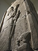 Hohe steinerne Siegesstele des Asarhaddon mit reliefierten Figuren und Keilschrift.