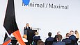 Ein Mann an einem Podium spricht zu einem Publikum