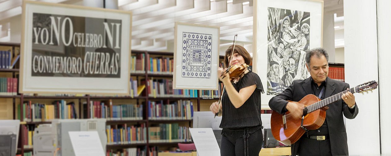 Ein Duo musiziert im Lesesaal des Ibero-Amerikanischen Instituts, im Hintergrund mexikanische Druckgrafiken