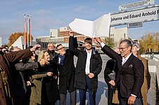 Personen ziehen eine weiße Hülle von einem Straßenschild