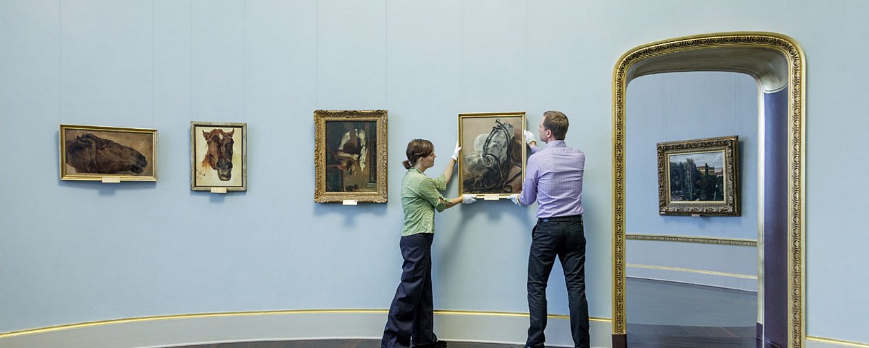 Zwei Personen positionieren ein Bild an der Wand