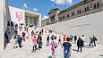 Viele sommerlich gekleidete Besucherinnen und Besucher auf dem großen Treppenaufgang der James-Simon-Galerie