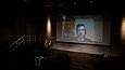 Eine Person wird via Livestream auf einer Leinwand zugeschaltet.