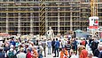 Mehrere Menschen sehen sich auf einer Baustelle eine überlegensgroße Skulptur an