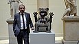 Ein Mann steht in einem Museum neben einer Skulptur