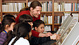 Mann zeigt mehreren Kindern Abbildungen in einem Buch