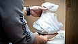 Hände packen ein in Papier eingepacktes Objekt in eine Kiste mit Schaumstoffauskleidung