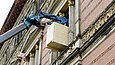 Ein Kran hebt eine Holzkiste durch ein Fenster ins Freie
