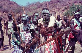Mehrere Männer mit traditionellen Holzschilden (guzuq) aus den Nuba-Fotografien im Nachlass Leni Riefenstahl.