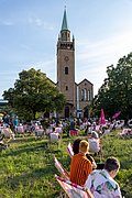 Menschen sitzen auf einer Wiese vor einer Kirche