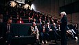Ein großer Sahl voller Menschen auf Kino-ähnlichen Stühlen.