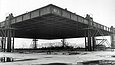 Historical photograph of the building of the Neue Nationalgalerie showing the steel roof being raised with hydraulic jacks