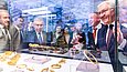 Mehrere Männer schauen in eine Glasvitrine mit Goldobjekten