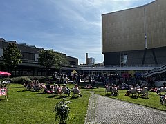 Menschen auf Liegestühlen im Philharmonischen Garten an einem sonnigen Tag