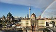 Blick auf die Dächer Berlins mit einem Regenbogen am Himmel