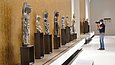 Diverse Sockel mit Buddha-Statuen vor einer goldenen Wand