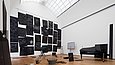 Künstlerische Installation mit Kreidezeichnungen an schwarzen Tafeln, einem schwarzen Flügel, einem Filmprojektor, einer Leiter und einer Zinkwanne in einem hohen Raum