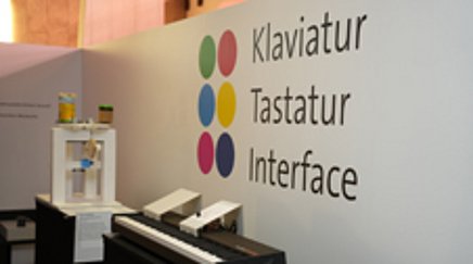 Blick in eine Ausstellung, an der Wand steht "Klaviatur – Tastatur – Interface"