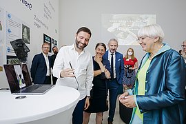 Eine Person demonstriert interessierten Zuhörer*innen eine Anwendung auf einem Smartphone