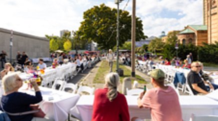 Menschen essen und reden an einer großen ovalen Tafel im Freien