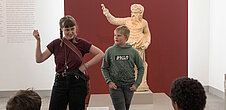 Eine junge Frau und ein Junge reden vor einer antiken Statue