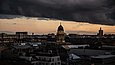 Blick auf die Dächer Berlins vor einem wolkenverhangenen Abendhimmel.