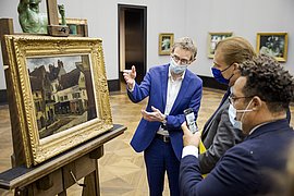Die Erbenvertreter Dorville mit Ralph Gleis vor dem Pissarro-Gemälde Drei Männer betrachten das Pissarro-Gemälde in der Alten Nationalgalerie