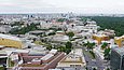 Computergenerierte Visualisierung eines von einer großen quadratischen Glasfläche geprägten Gebäudes in urbaner Stadtlandschaft