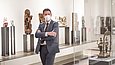 Mann in einem Ausstellungsraum mit Vitrinen voll indischen Objekten