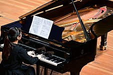 Frau sitzt an einem Flügel und spielt Klavier