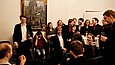 Mehrere Menschen sitzen und stehen verteilt in einem Raum