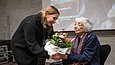 Eine junge Frau überreicht einer alten Frau einen Blumenstrauß