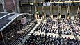 Blick von oben in eine Halle, in der ein Publikum vor einer Bühne sitzt