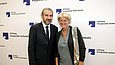 Ein Mann und eine Frau posieren vor einer Stellwand mit dem SPK-Logo