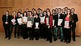 Mehrere Menschen halten Urkunden in der Hand und posieren für die Kamera