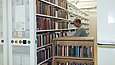 Ein Mann räumt von einem Bücherwagen Bücher in Regale ein