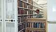 Ein Mann räumt von einem Bücherwagen Bücher in Regale ein