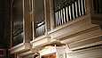 Ein Mann spielt Orgel, während ihm ein anderer Mann über die Schulter blickt