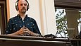 Ein Mann mit Kopfhörern steht an einem DJ-Mischpult