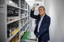 Ludger Derenthal steht zwischen Archivregalen mit beschrifteten Archivboxen.