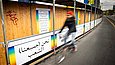 Ein Fahrradfahrer passiert die Plakate am Bauzaun